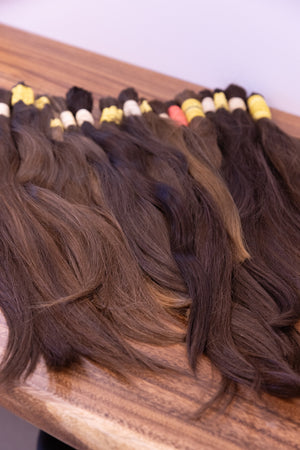 Raw European hair bundles in natural brown shades laid out on the grading table